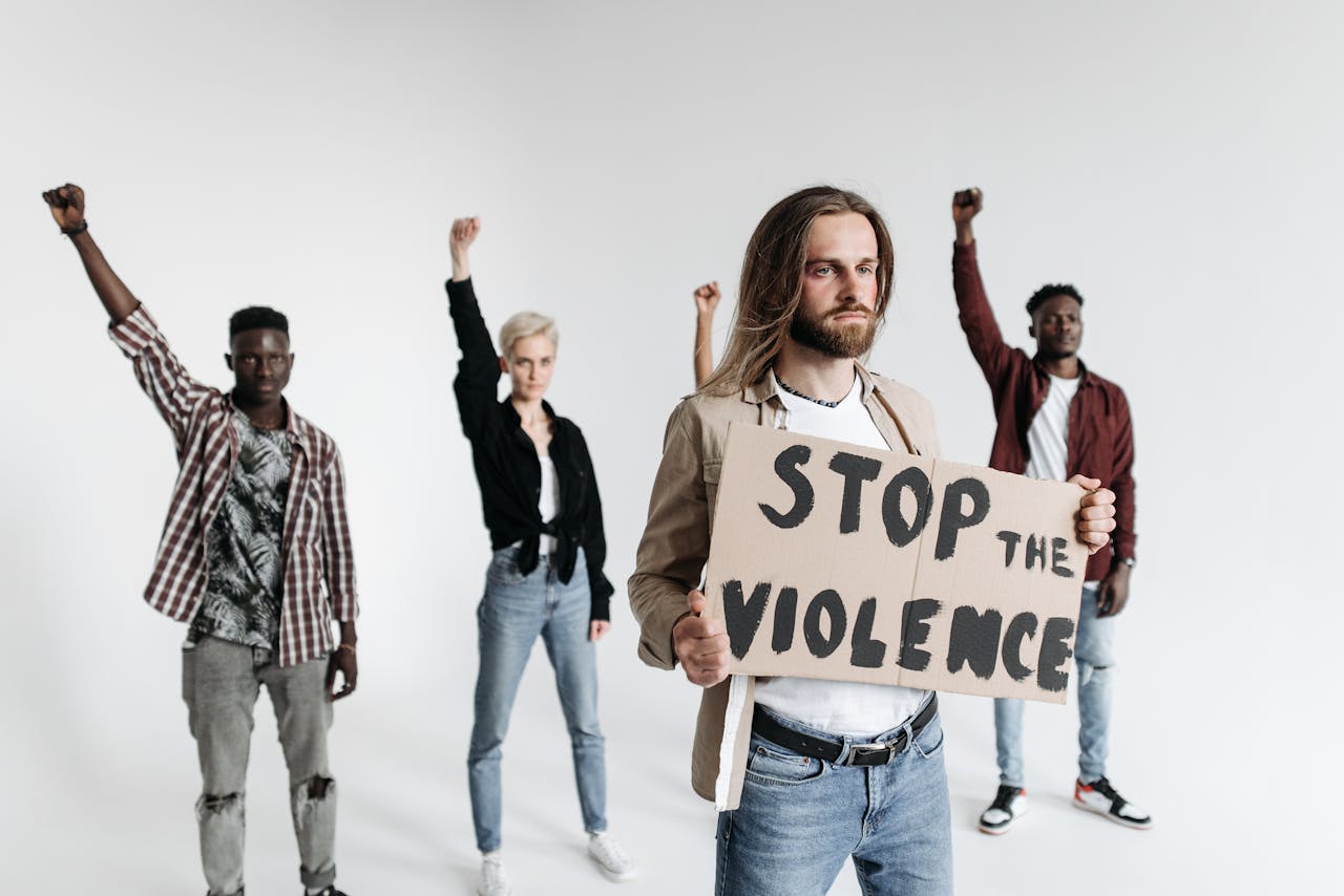 A diverse group of people protesting against violence, holding a sign indoors.